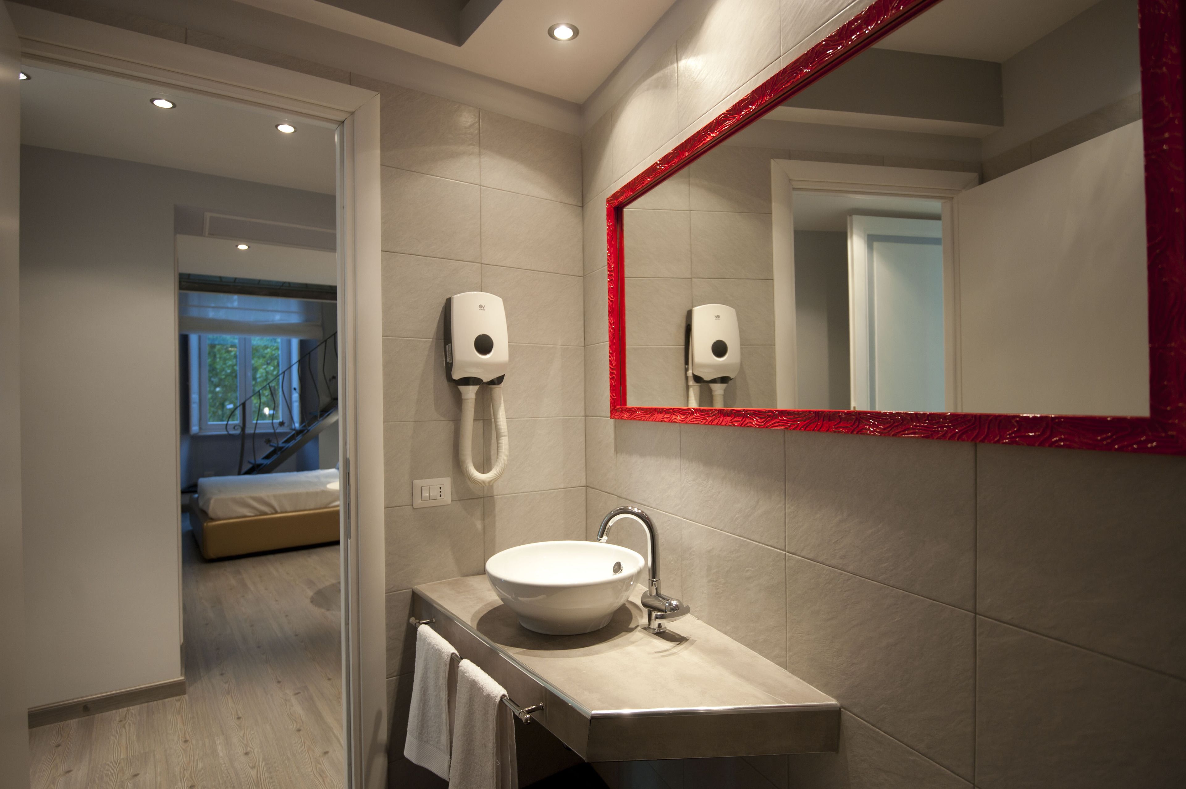 Een moderne badkamer met een grote spiegel, een wastafel en twee handdrogers.