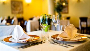 A dining table set with plates, napkins, cutlery, and glasses, indicating a formal dining arrangement.