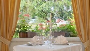 A table set for two with a view of a garden through a window with curtains. - Al Poggio Verde (Barghe)