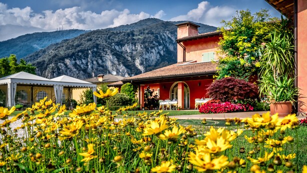 A mountain house with a red facade, a garden with yellow flowers, and a white tent in the foreground. - Al Poggio Verde (Barghe)
