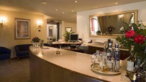 A hotel reception area with a curved counter, a large mirror, and a selection of bottled beverages. - Al Poggio Verde (Barghe)