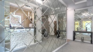 Eine moderne Hotelhalle mit einer geometrischen Glasabtrennung, einem Empfangsbereich und einer Wandverkleidung.