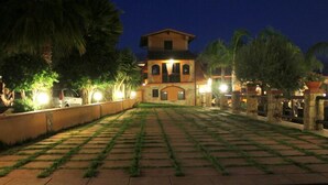 A courtyard with a stone pathway leading to a building with arched windows and a balcony. - Borgo dei Vigneti (Agrigento)