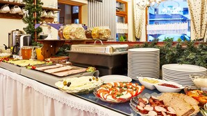 A buffet with various food items, including salads, meats, and desserts, in a well-lit room with a window view.