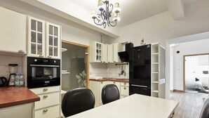 A modern kitchen with white cabinetry, a black refrigerator, and a dining area with a white table and black chairs.