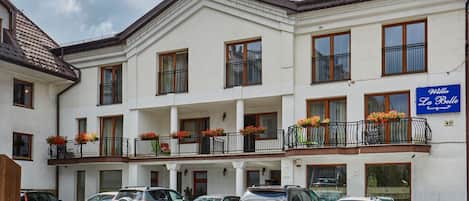 A multi-story hotel with a white facade, balconies with flower boxes, and a sign reading "Villa La Belle."