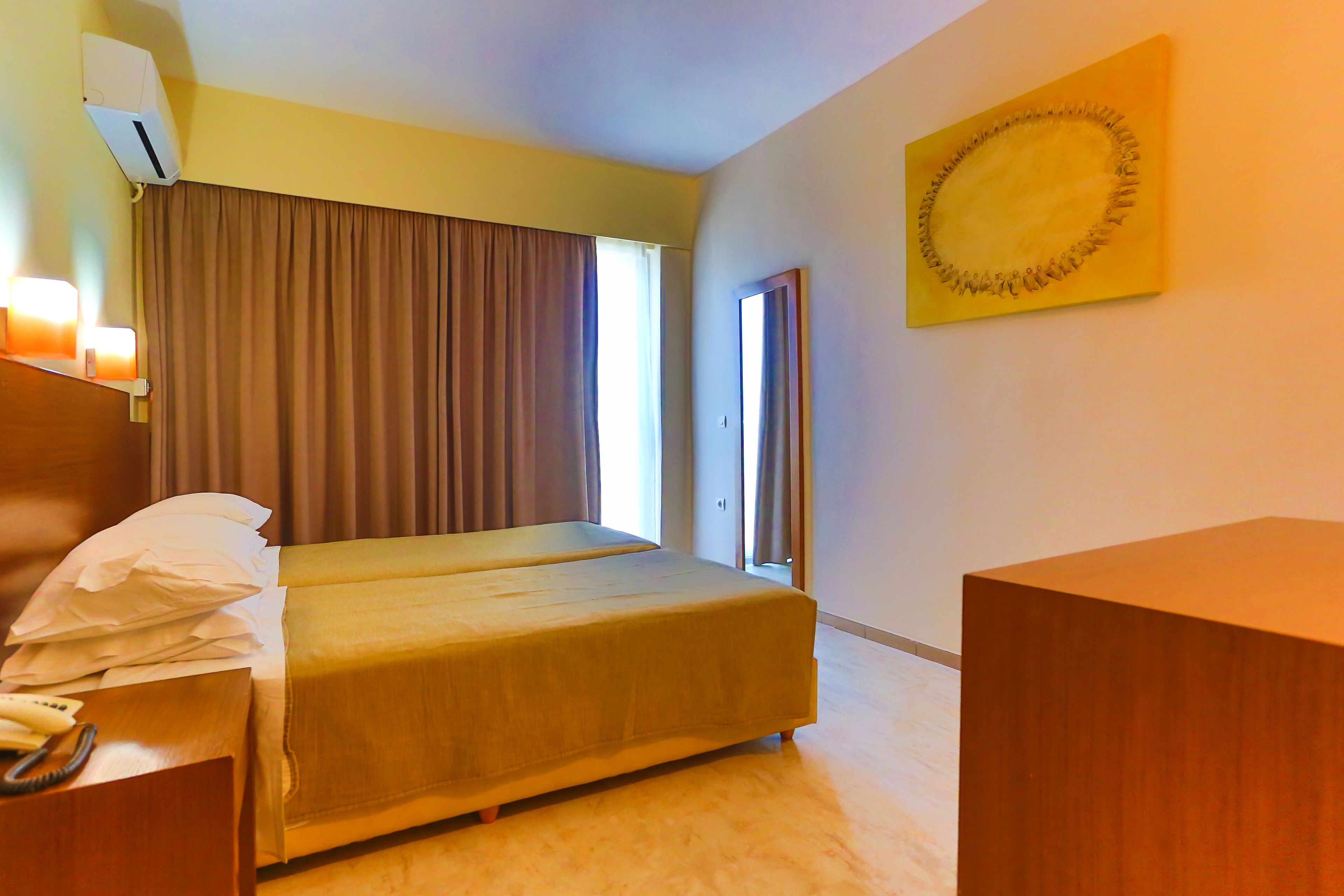 Una habitación de hotel con cama, mesita de noche y escritorio con lámpara.