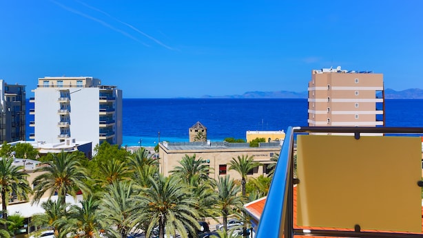 A coastal cityscape with modern buildings, a clear blue sky, and a view of the sea. - Rodian Gallery Hotel Apartments (Rhodes)