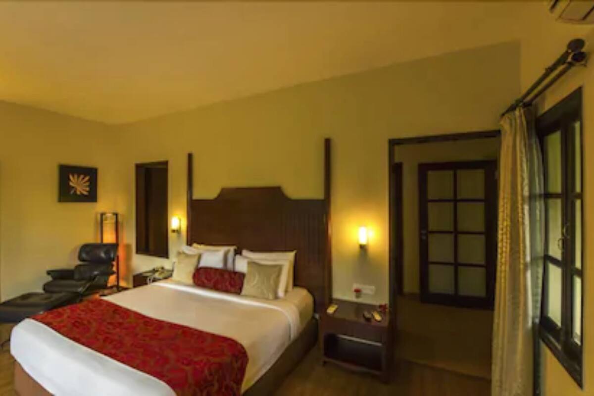 Una habitación de hotel con una cama grande, una mesita de noche, una silla y una puerta.