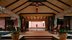 A spacious lobby with a high ceiling, a central staircase, and potted plants. - The Windflower Resorts & Spa (Somvarpet)