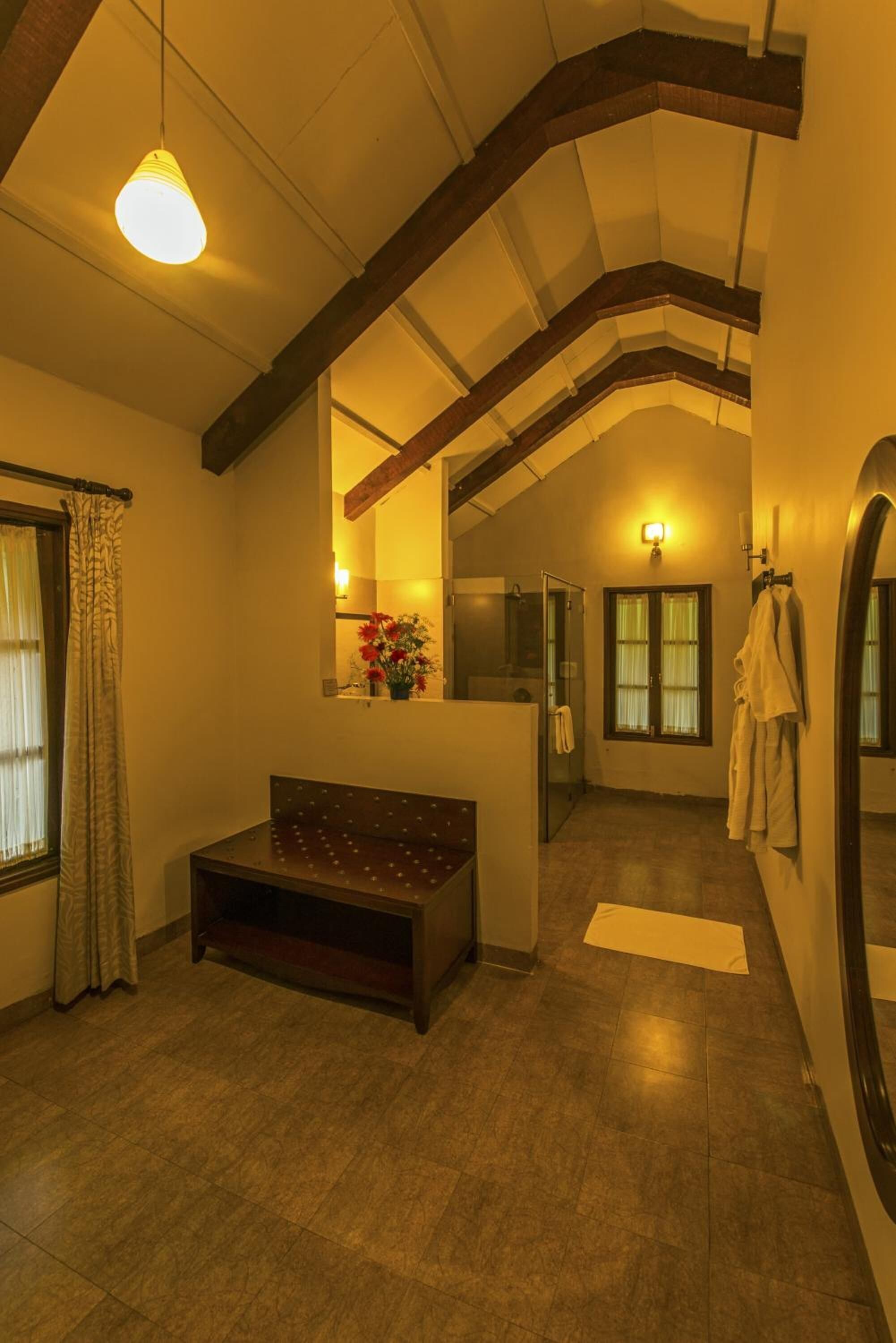 A bathroom with a wooden bench, a mirror, and a shower.