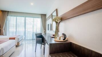 A modern hotel room with a bed, a desk with a vase of flowers, a chair, and a large window with curtains.