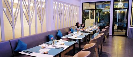 Un restaurant avec de longues tables, des coussins bleus et un décor intérieur moderne.
