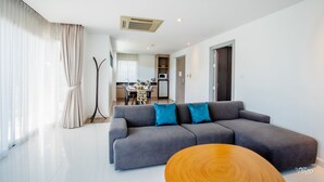 Una sala de estar moderna con un sofá seccional gris, una mesa de centro de madera y un comedor al fondo.