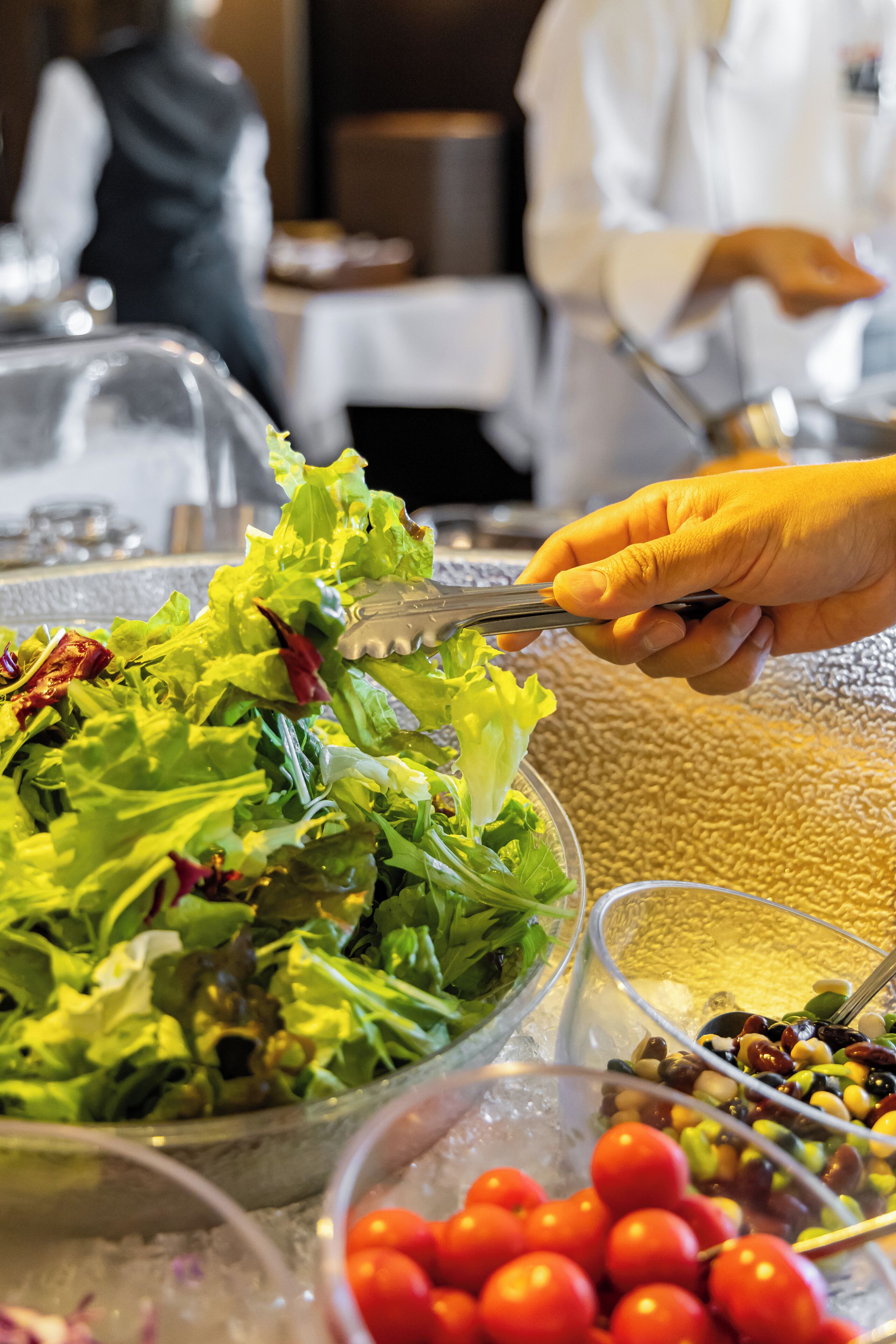 A buffet with various food items including a salad, cherry tomatoes, and olives.