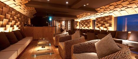 A modern lounge area with wooden panel walls, cushioned seating, and a glass coffee table.