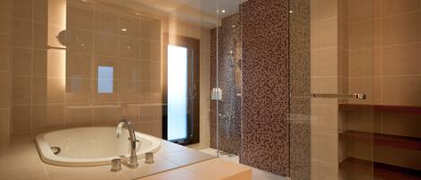 A modern bathroom with a large bathtub, a glass-enclosed shower, and a tiled wall with a mosaic pattern.