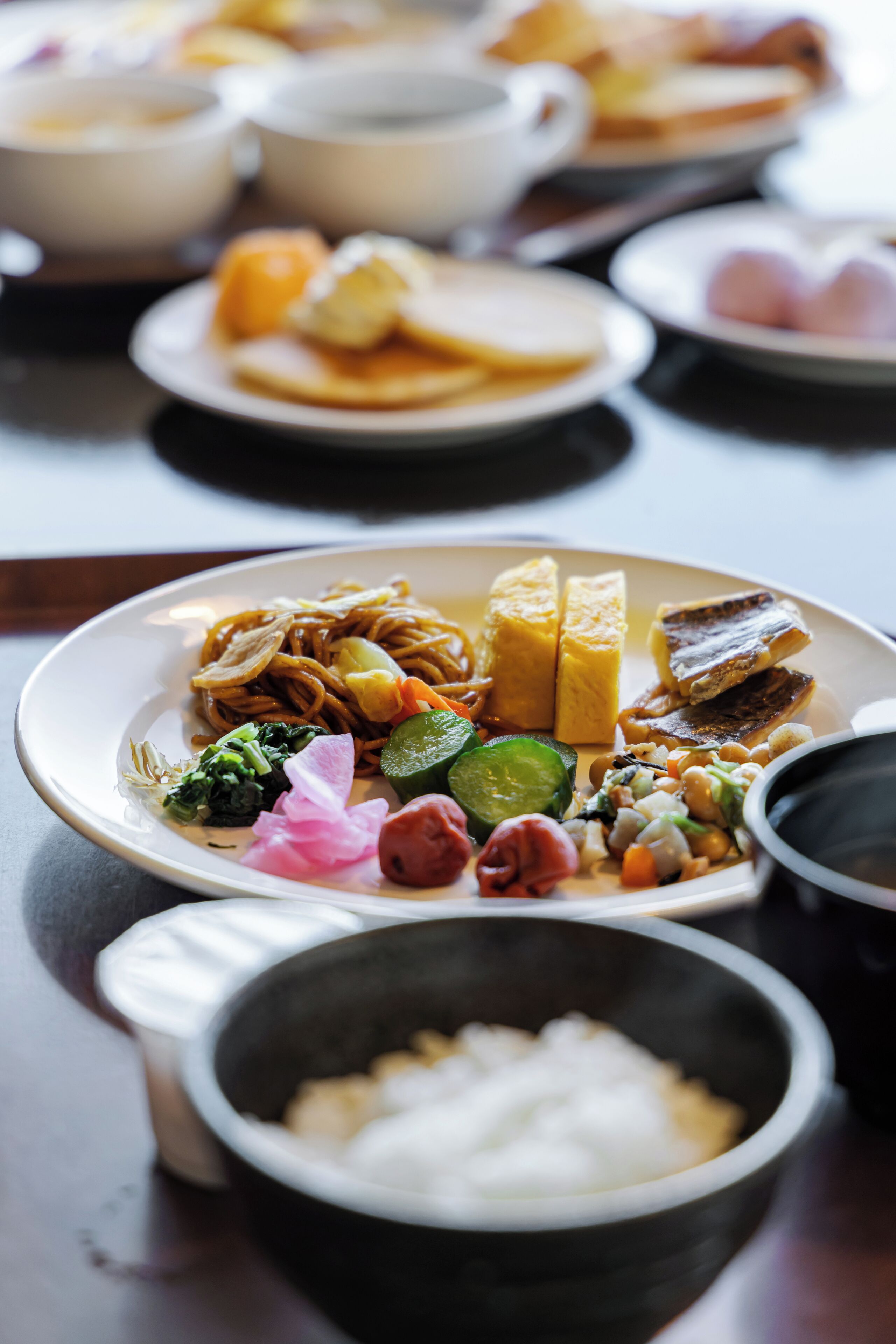 A dining table with various dishes, including noodles, vegetables, and tofu.