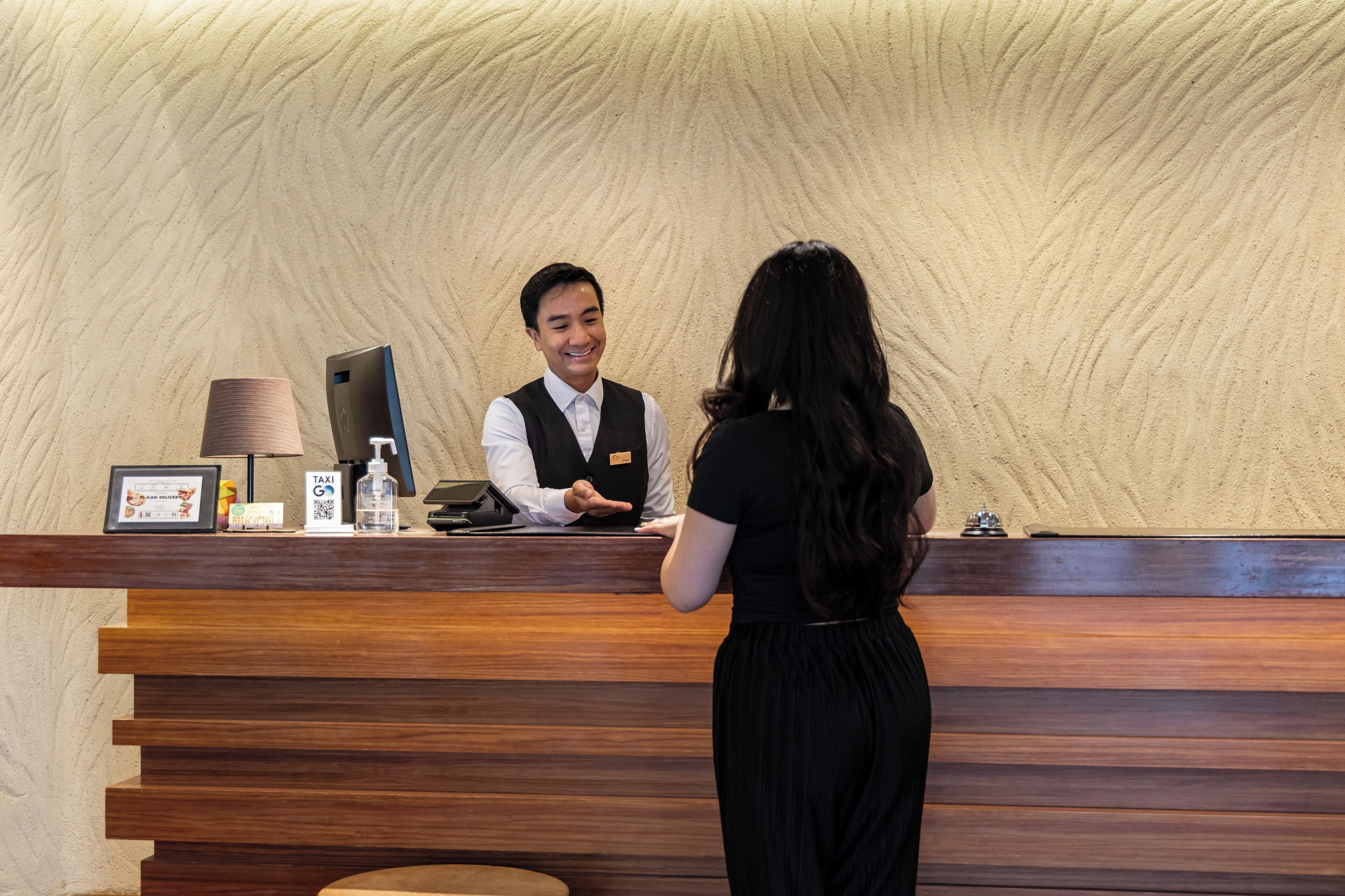 Un mostrador de recepción con detalles de madera y una pared con textura al fondo.