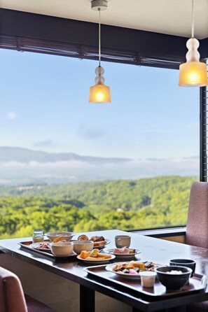 A dining table with breakfast items and a view of a forested landscape. - One Niseko Resort Towers (Niseko)