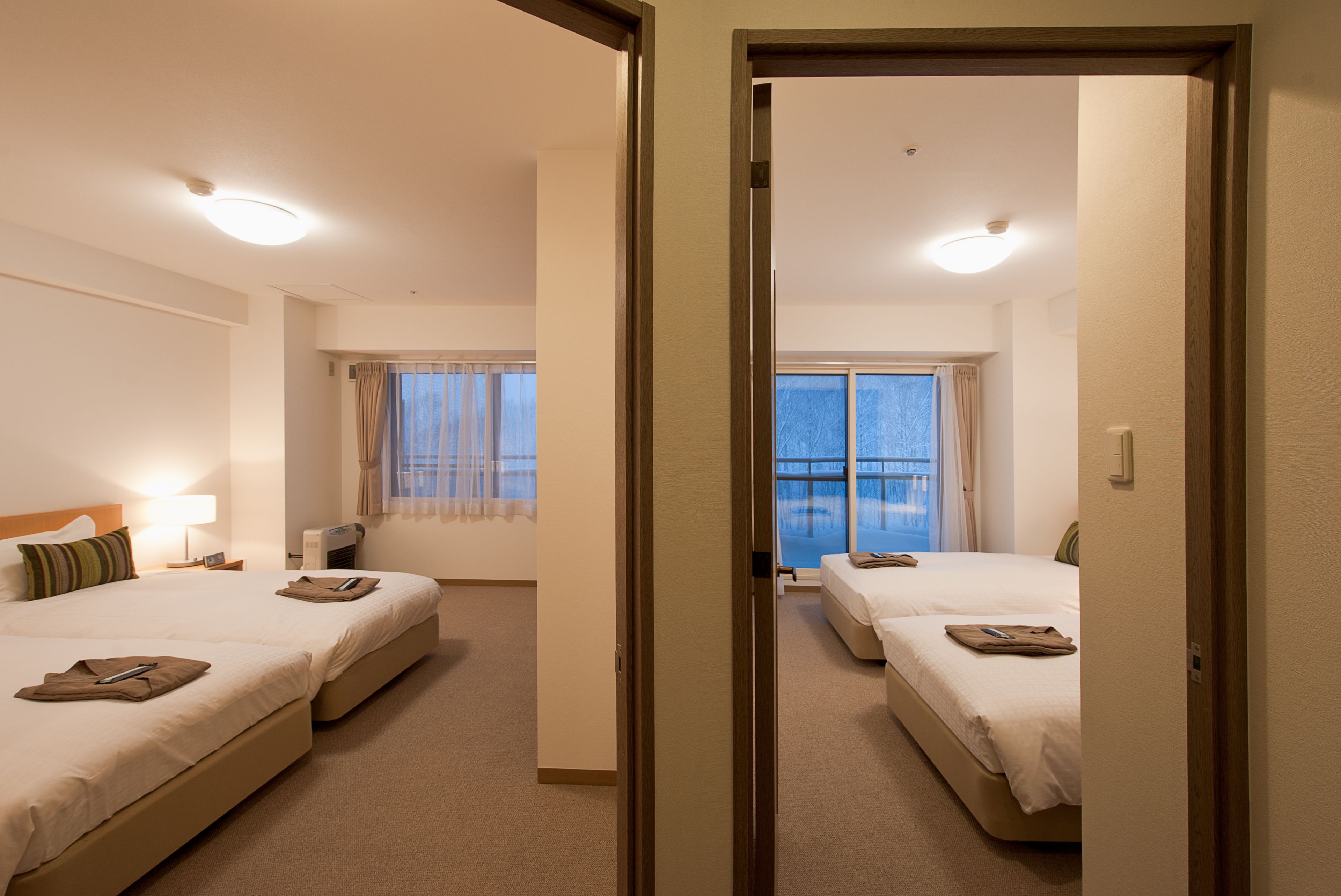 A hotel room with two beds, a sitting area, and a view of the sea.