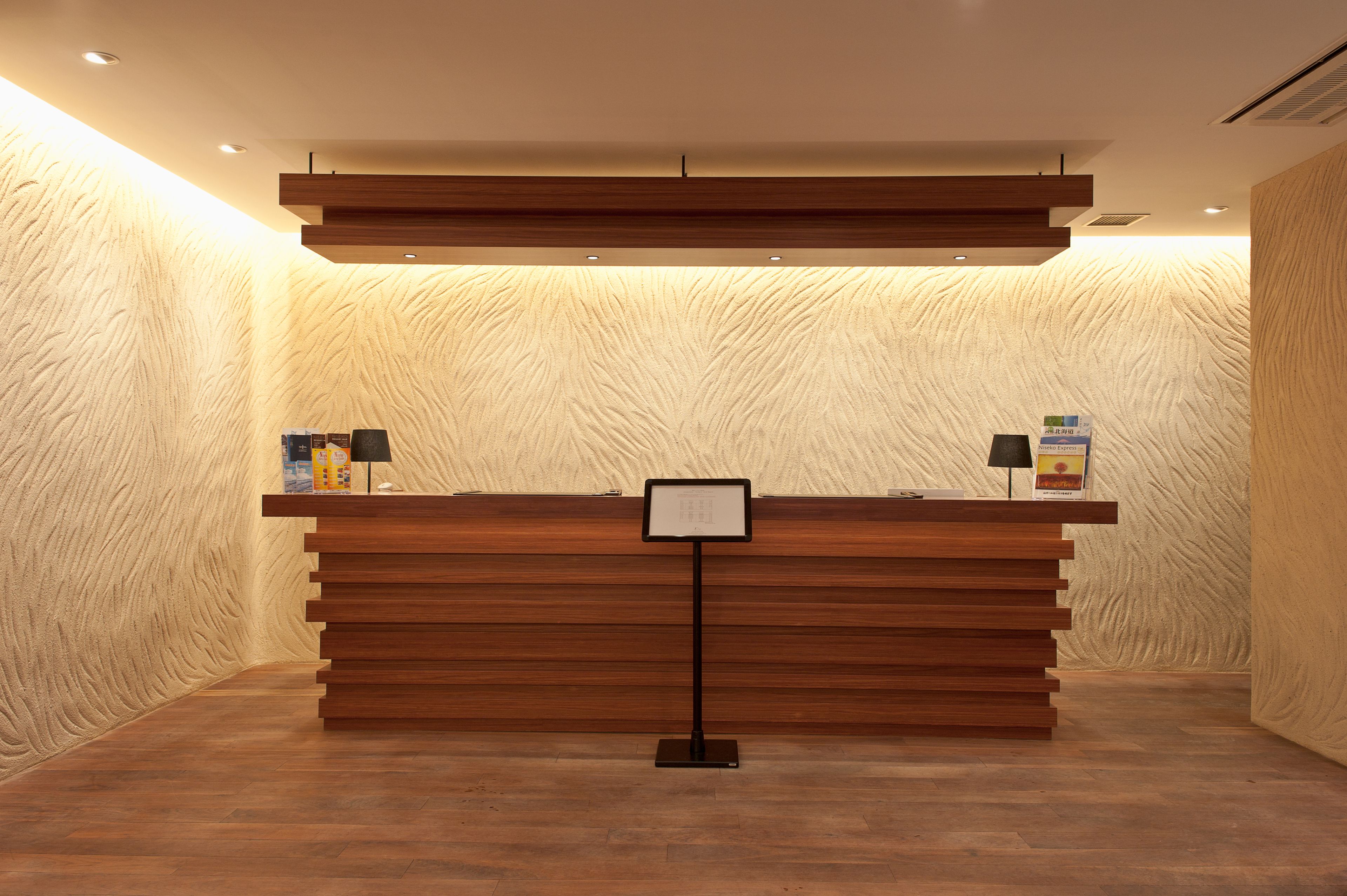 A reception desk with a wooden finish, a black sign stand, and a textured wall in the background.