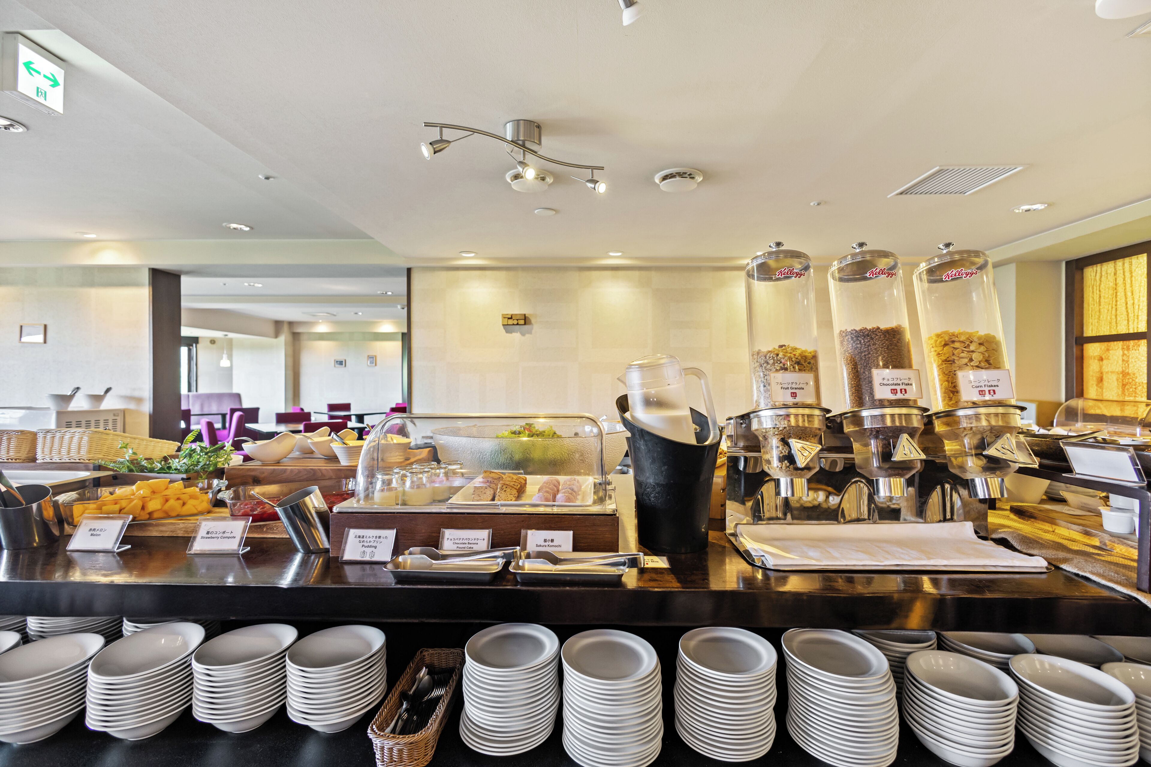 A buffet setup with various food items, a coffee station, and stacked plates.