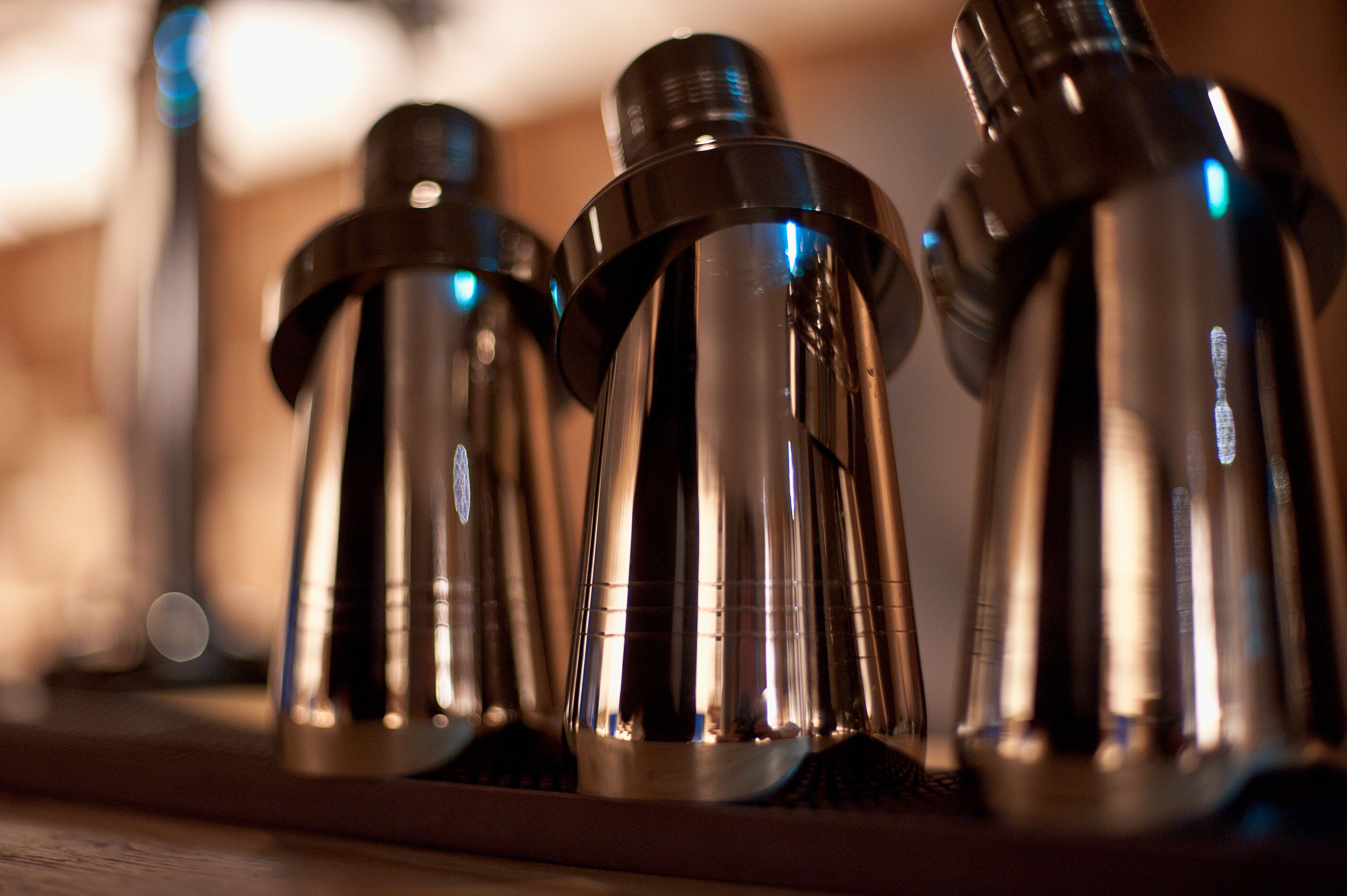 A row of metallic, cylindrical objects with a reflective surface, likely serving as decorative or functional items in a setting with warm ambient lighting.