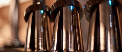 A row of metallic, cylindrical objects with a reflective surface, likely serving as decorative or functional items in a setting with warm ambient lighting.