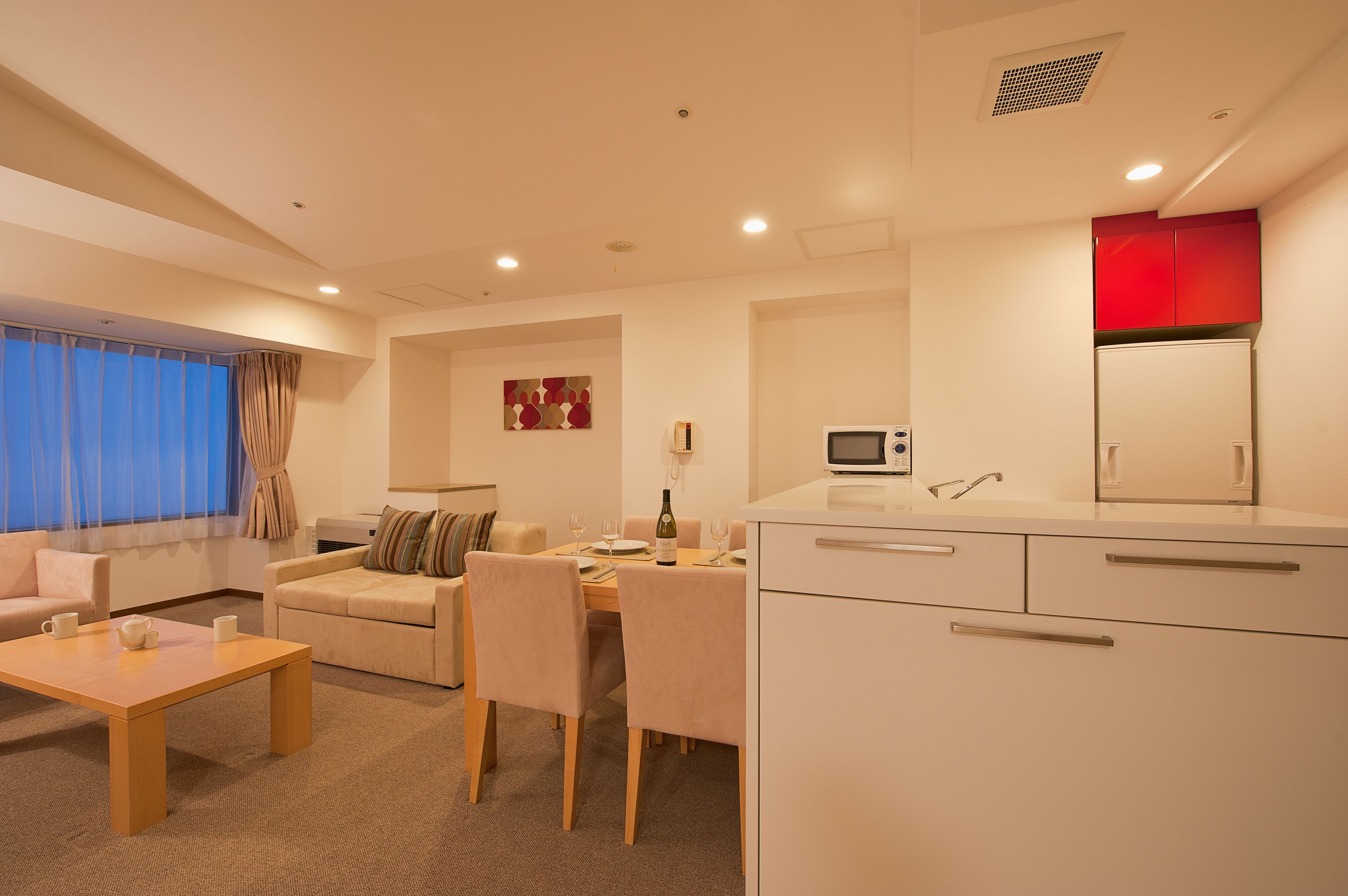 A modern living room with a sofa, a dining table, and a kitchen area with a microwave.