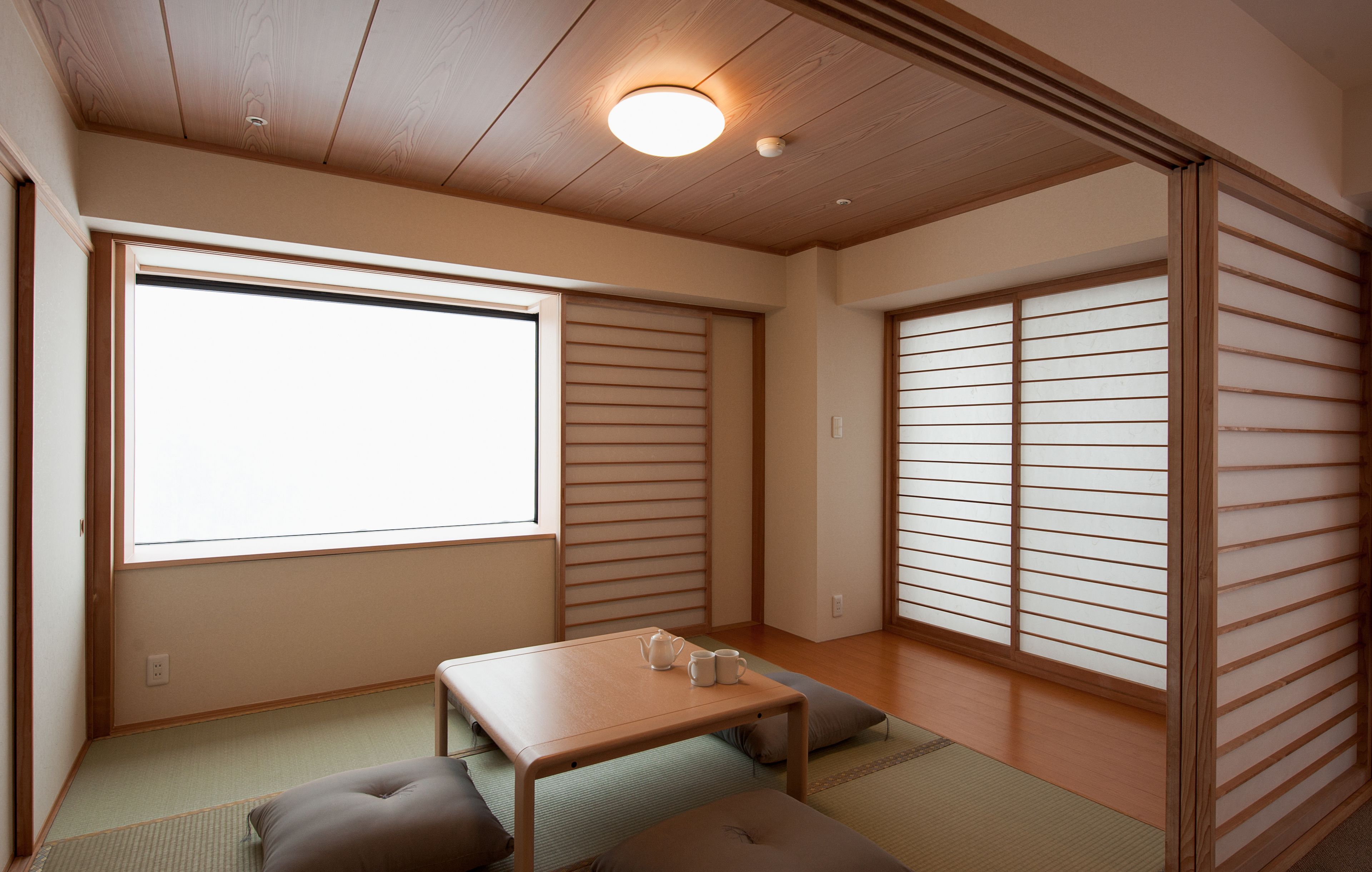 A traditional Japanese room with tatami flooring, a low wooden table, and shoji screens.