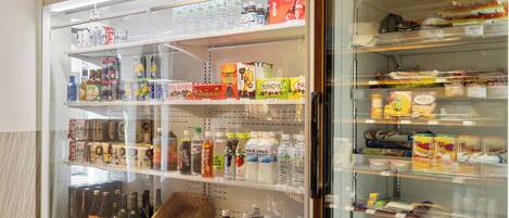 Un refrigerador exhibe diversas bebidas y aperitivos.