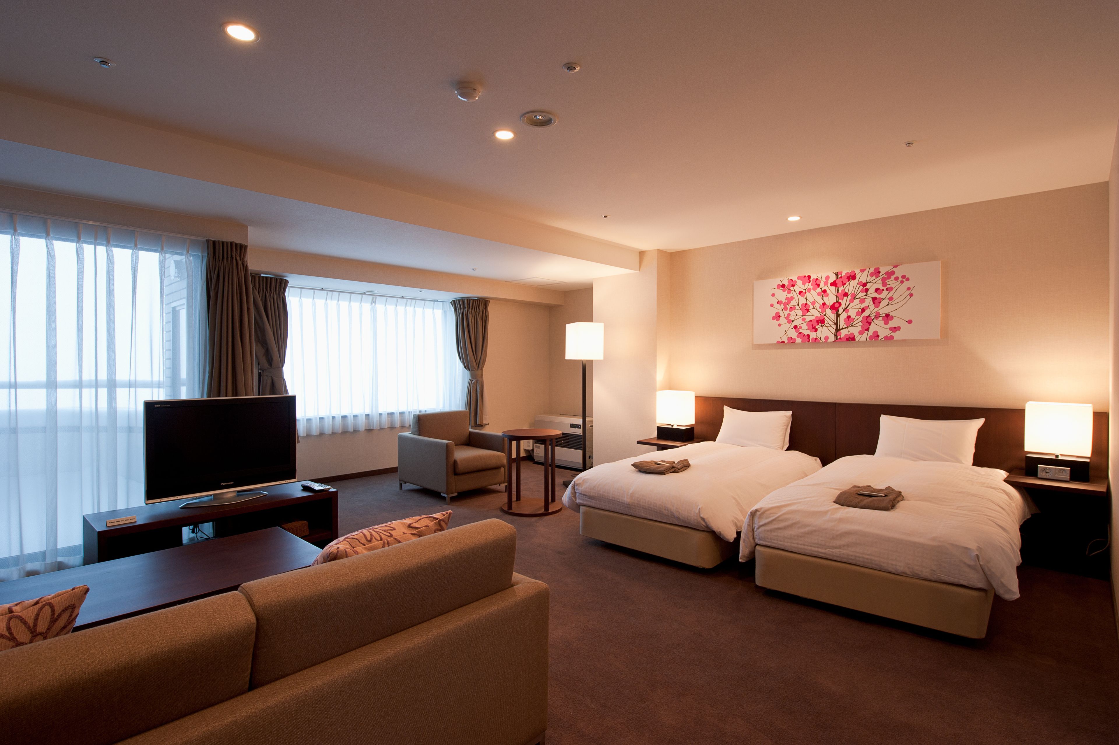 A hotel room with a large bed, a sofa, a TV, and a desk.