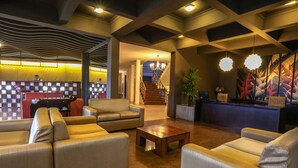 A spacious lobby with leather sofas, a wooden coffee table, and a reception desk. - The Tourmaline (Kandy)