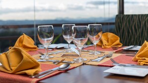 A dining table set with four wine glasses, yellow napkins, and silverware. - The Tourmaline (Kandy)