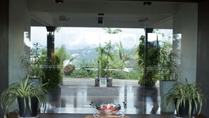 A reception area with a glass partition, potted plants, and a central decorative bowl with candles. - The Tourmaline (Kandy)