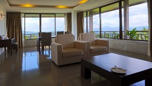A spacious room with large windows, a dining area, and two sofas. - The Tourmaline (Kandy)