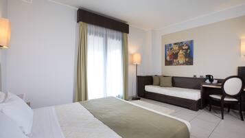 Ein Hotelzimmer mit Bett, Schreibtisch, Stuhl, einem Gemälde an der Wand und einem Vorhangfenster.