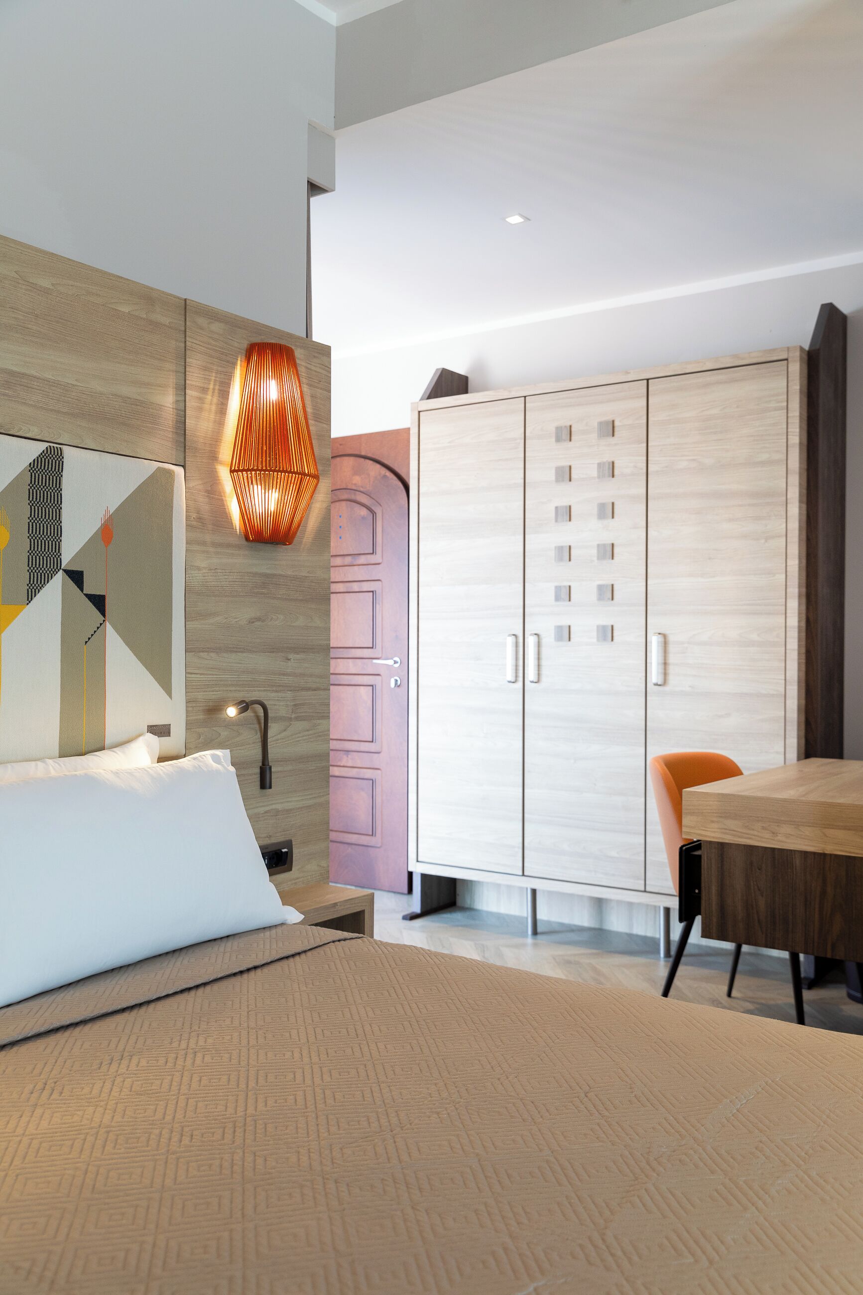 Ein modernes Schlafzimmer mit einem Bett, einem Holzschrank, einem Tisch und einem Stuhl.