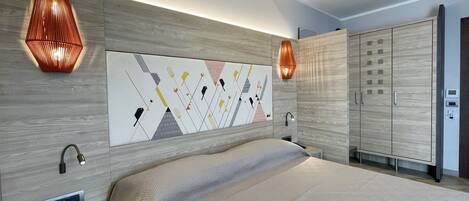 A modern bedroom with a large bed, a wall-mounted artwork, and a wardrobe.