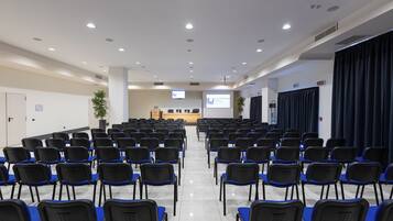 A conference room with rows of chairs, a podium, and a projection screen.