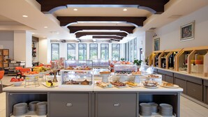 A buffet with various food items and a seating area with orange chairs. - Lu' Hotel Carbonia (Carbonia)