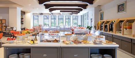 A buffet with various food items and a seating area with orange chairs.