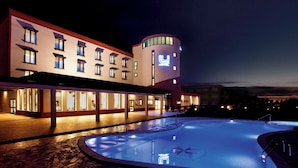 A hotel with a swimming pool, multiple floors, and a distinctive curved tower. - Lu' Hotel Carbonia (Carbonia)