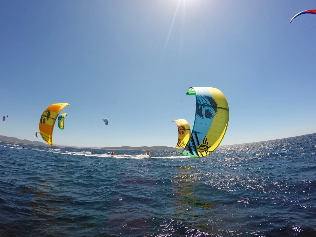 A clear view of the sea with multiple kitesurfing activities.
