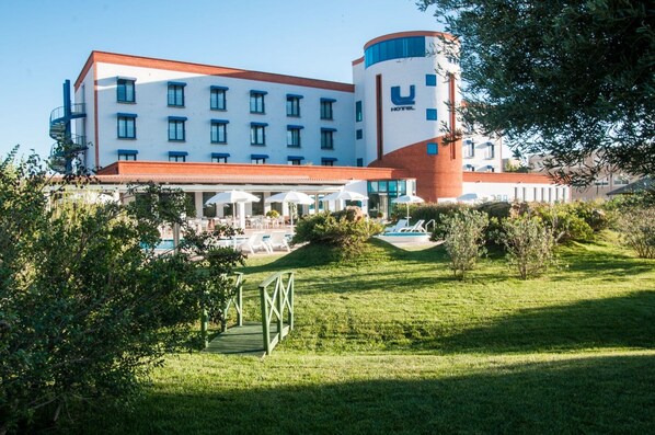 Un hotel con piscina, zona de estar exterior y césped bien cuidado.