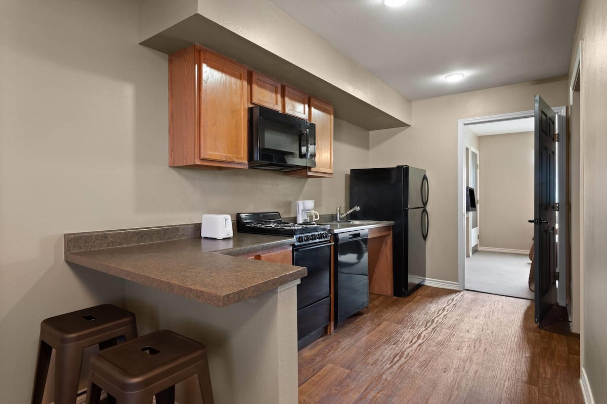 A kitchen with wooden cabinets, a microwave, a stove, a refrigerator, and a toaster.