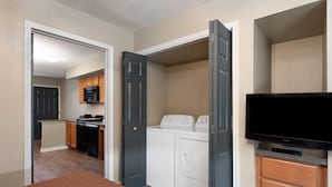 A hotel room with a bed, a TV, a washer and dryer, and a kitchenette. - Eagle's Den Suites Carrizo Springs a Travelodge by Wyndham (Carrizo Springs)