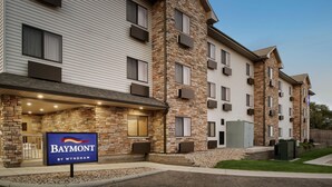 Un hotel de varios pisos con fachada de piedra, un letrero que dice 'Baymont by Wyndham' y una entrada cubierta.