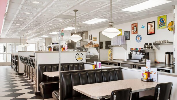 Un restaurante con cabinas, una barra y una zona de cocina.
